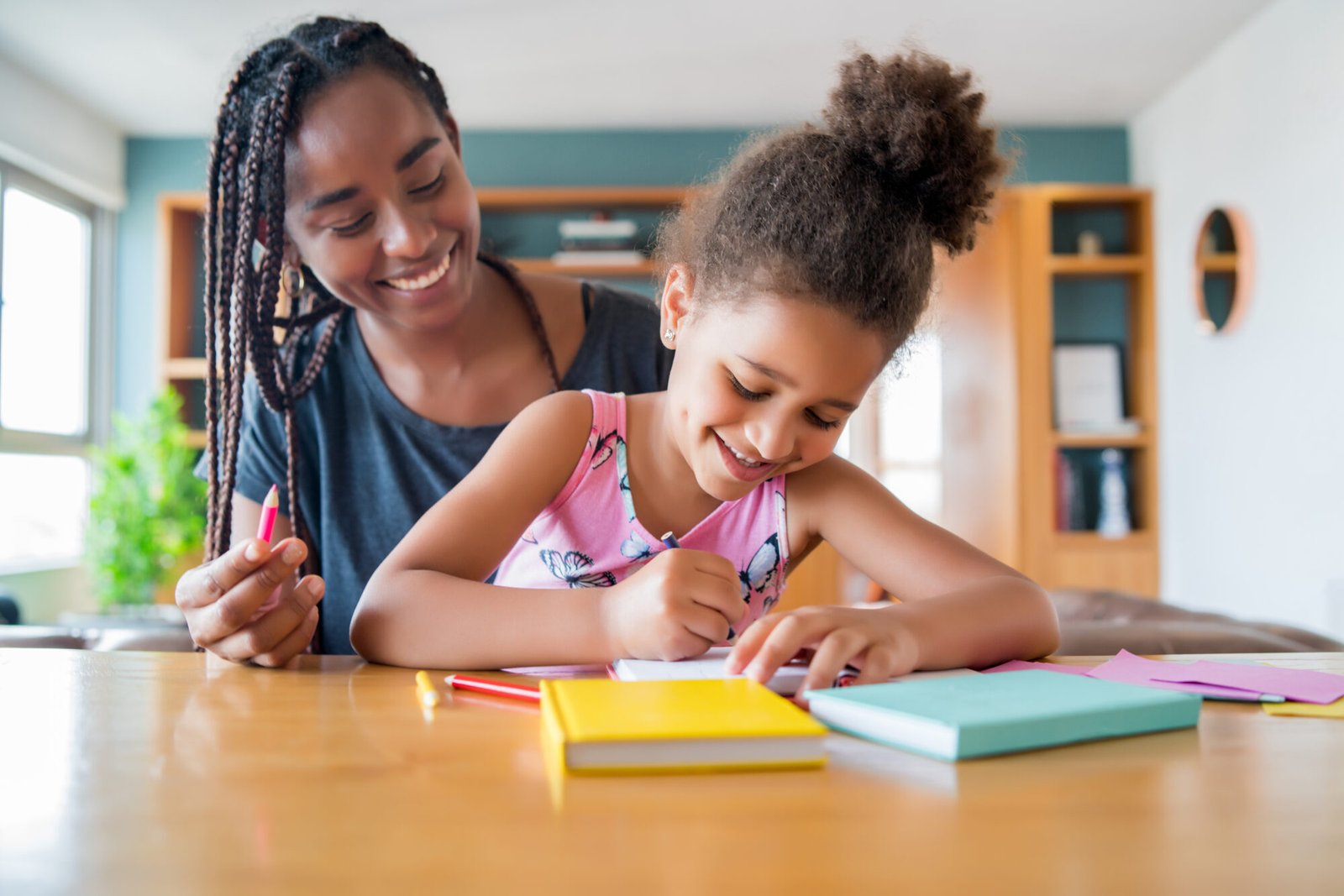 A mother and child planning a homeschool routine together at a sunlit desk in their home in South Africa