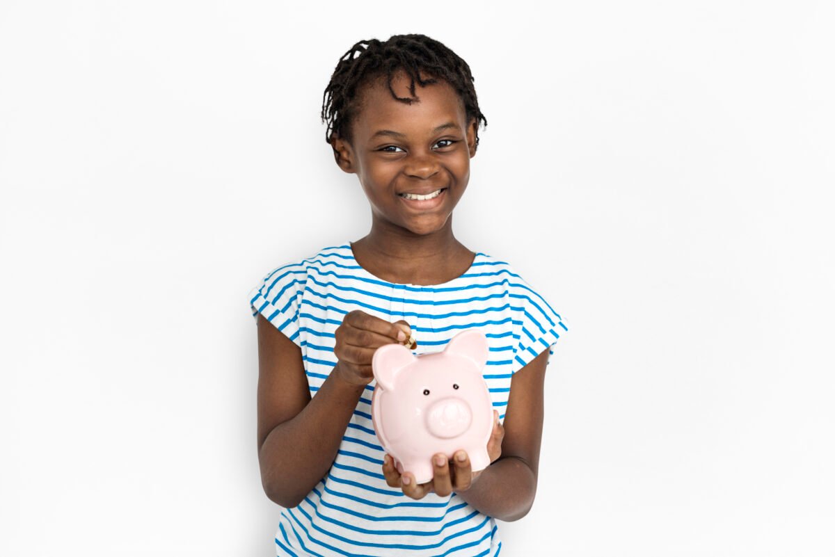A-child-learning-about-teaching-kids-about-money-by-putting-a-coin-in-a-piggy-bank