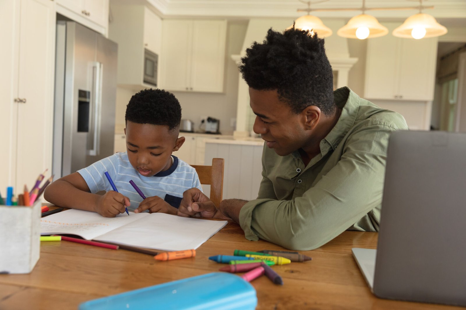 a-man-homeschooling-a-boy-in-a-supportive-environment-by-helping-him-write-in-a-workbook
